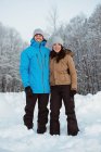 Ritratto di coppia sorridente in piedi su un paesaggio innevato — Foto stock