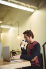 Uomo che utilizza il computer portatile mentre prende il caffè in caffetteria — Foto stock