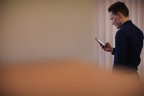 Мужчина исполнительный с помощью мобильного телефона в офисе — стоковое фото