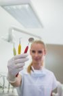 Улыбающийся стоматолог, держащий стоматологические инструменты в клинике — стоковое фото