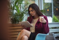 Mulher de negócios bonita usando tablet digital enquanto toma café no café — Fotografia de Stock