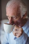 Крупный план пожилого человека, пьющего кофе в спальне дома — стоковое фото