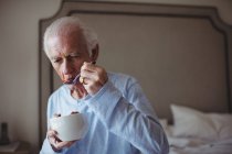 Senior man having breakfast in bedroom at home — Stock Photo