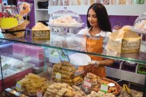 Fêmea lojista servindo doces turcos em prato no balcão na loja — Fotografia de Stock