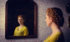 Bella donna in piedi davanti allo specchio e sorridente — Foto stock