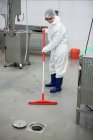 Женщины-сотрудники чистят пол на мясокомбинате — стоковое фото