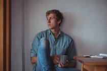 Удумливий чоловік тримає чашку кави вдома — стокове фото