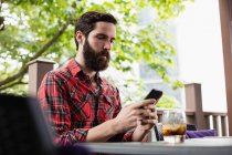 Людина використовує мобільний телефон, сидячи в барі — стокове фото