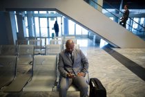 Uomo d'affari che utilizza il telefono cellulare in zona di attesa in aeroporto — Foto stock