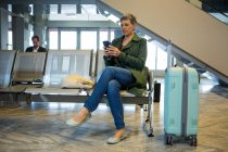 Жінка-пасажир використовує свій мобільний телефон в зоні очікування в терміналі аеропорту — стокове фото