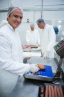 Portrait de boucher pesant des paquets de viande hachée à l'usine de viande — Photo de stock