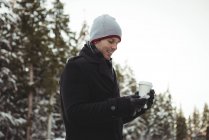 Людина в теплому одязі за допомогою мобільного телефону взимку — стокове фото