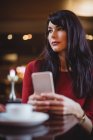 Frau hält Handy in Restaurant — Stockfoto