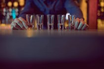 Barkeeper platziert Schnapsgläser hintereinander am Tresen in Bar — Stockfoto