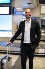 Porträt eines Geschäftsmannes, der mit Gepäck im Wartebereich des Flughafens steht — Stockfoto