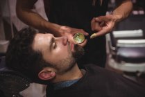 Milieu de section de barbier appliquer de la crème sur la barbe du client dans le salon de coiffure — Photo de stock