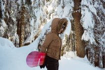 Жінка зі сноубордом, що йде на засніженій горі — стокове фото