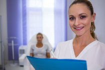 Retrato de una doctora sonriente con informe médico - foto de stock