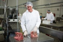 Retrato de açougueiro cortando carne na fábrica de carne — Fotografia de Stock