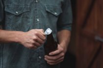 Primer plano del hombre abriendo una botella de cerveza - foto de stock
