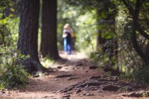 Blurred woman at distance jogging on the forest path — Stock Photo
