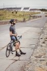 Athlete standing with bicycle on country road — Stock Photo