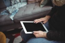 Partie médiane de la femme utilisant une tablette numérique dans le salon à la maison — Photo de stock