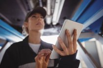 Жінка-механік використовує цифровий планшет під машиною в ремонтному гаражі — стокове фото