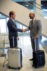 Business people shaking hand in waiting area with airport — Stock Photo