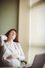 Donna d'affari incinta che tiene la schiena dolorosa mentre si siede sulla sedia in ufficio — Foto stock