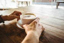 Руки женщины, держащей чашку кофе в кафе — стоковое фото