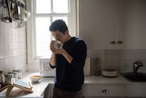 Uomo che utilizza tablet digitale mentre prende una tazza di caffè a casa — Foto stock