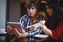 Casal usando digital enquanto toma café no restaurante — Fotografia de Stock