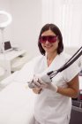 Médecin dans des lunettes de protection tenant épilateur en clinique — Photo de stock