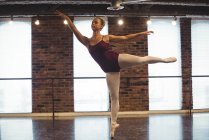 Ballerine pratiquant la danse de ballet à la barre en studio de ballet — Photo de stock