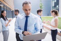 Geschäftsmann benutzt Laptop vor Bürogebäude — Stockfoto