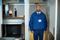 Portrait of airport security officer standing in metal detector door at airport terminal — Stock Photo