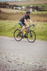 Male athlete riding sport bicycle on rural road — Stock Photo