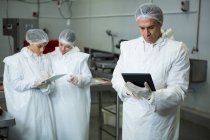 Tecnici che utilizzano tablet digitale in fabbrica di carne — Foto stock