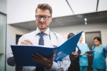 Лікар дивиться на медичну доповідь в лікарняному коридорі — стокове фото