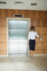 Visão traseira da mulher de negócios esperando por um elevador no escritório — Fotografia de Stock