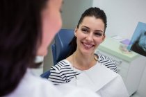 Paciente do sexo feminino sorrindo enquanto conversa com o médico na clínica — Fotografia de Stock