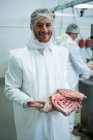 Portrait of butcher holding meat at meat factory — Stock Photo