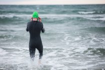 Rear view of athlete in wet suit wearing swimming glasses in sea — Stock Photo