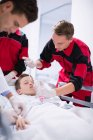 Medici che regolano la maschera di ossigeno mentre spingono il paziente al pronto soccorso in ospedale — Foto stock