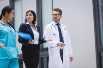 Médicos y enfermeras interactúan mientras caminan en los locales del hospital - foto de stock