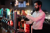 Barman llenando cerveza de la barra de la bomba en barra contador - foto de stock