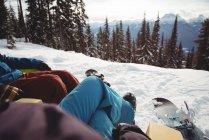 Section basse du couple assis à la montagne enneigée — Photo de stock
