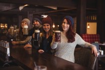 Portrait d'amis tenant des verres à bière au comptoir du bar — Photo de stock