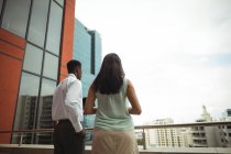 Rear view of businessman and a colleague standing in office balcony — Stock Photo